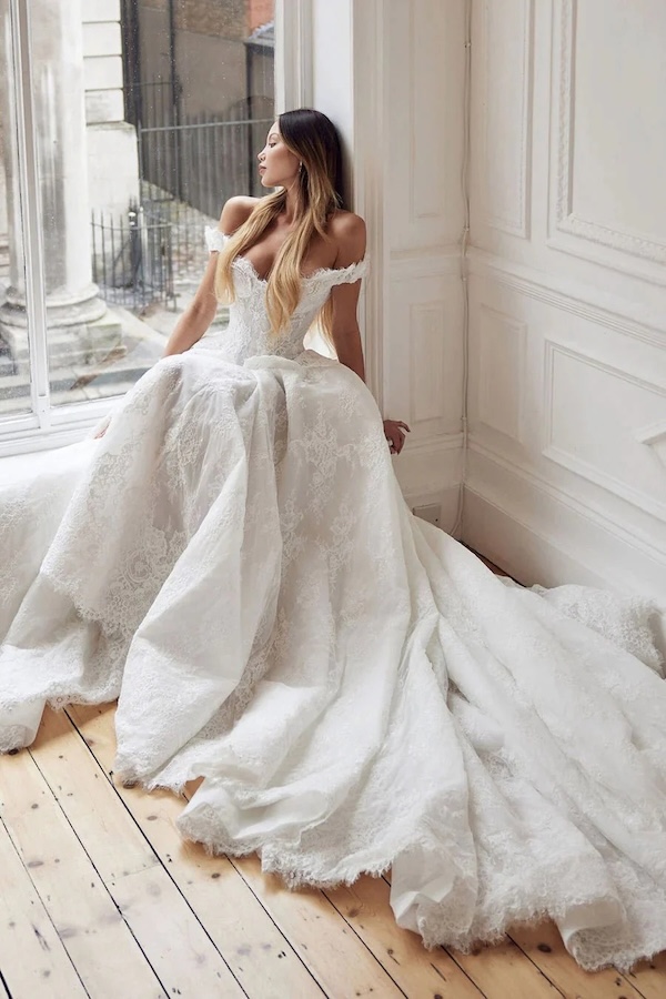 A bride wearing a flowing dress looking out a window