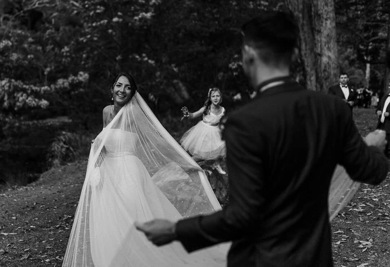 Black & white wedding photograph of a couple spreading the bride's veil