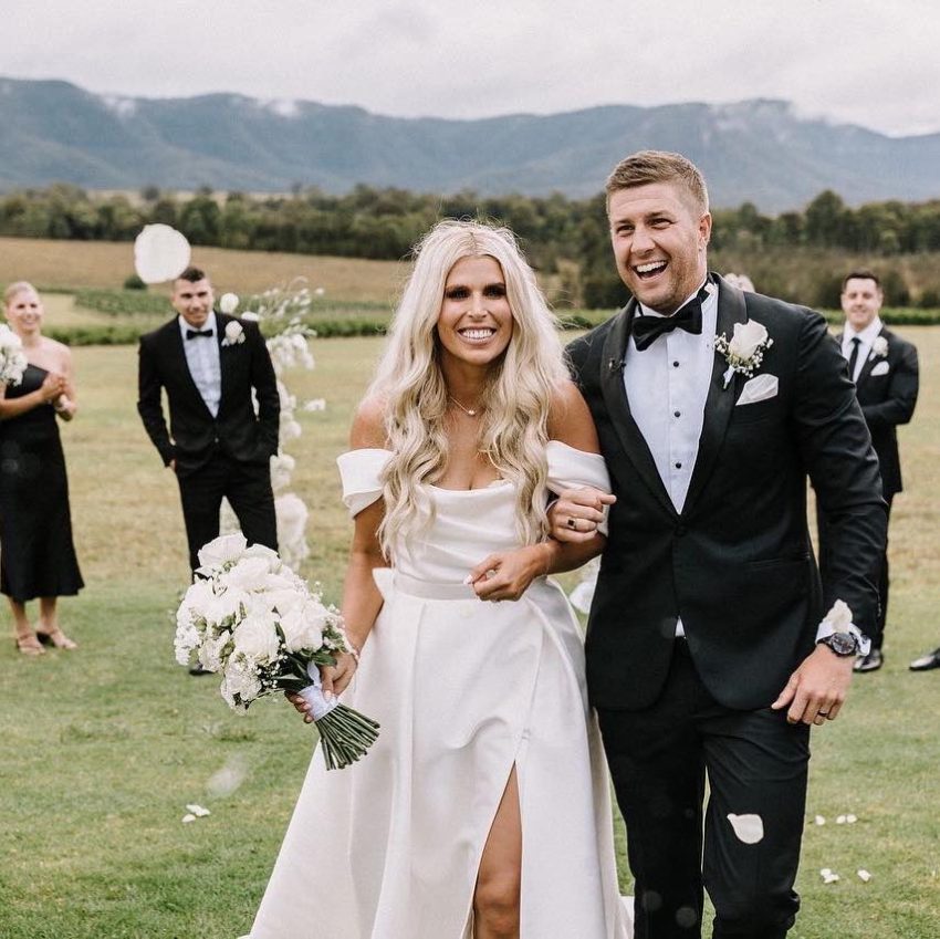 Newlyweds walk down aisle, surrounded by guests, on their wedding day.