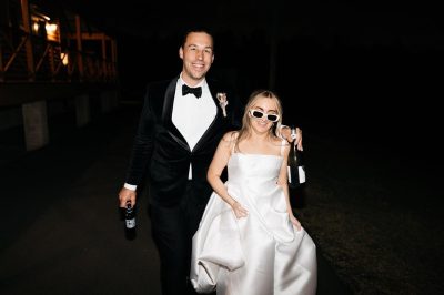 A bride and groom walking down a street at night.