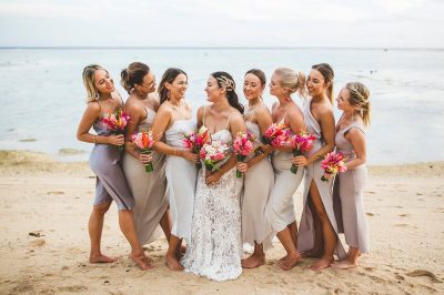 Bridesmaids smiling and posing for a photo on the beach.