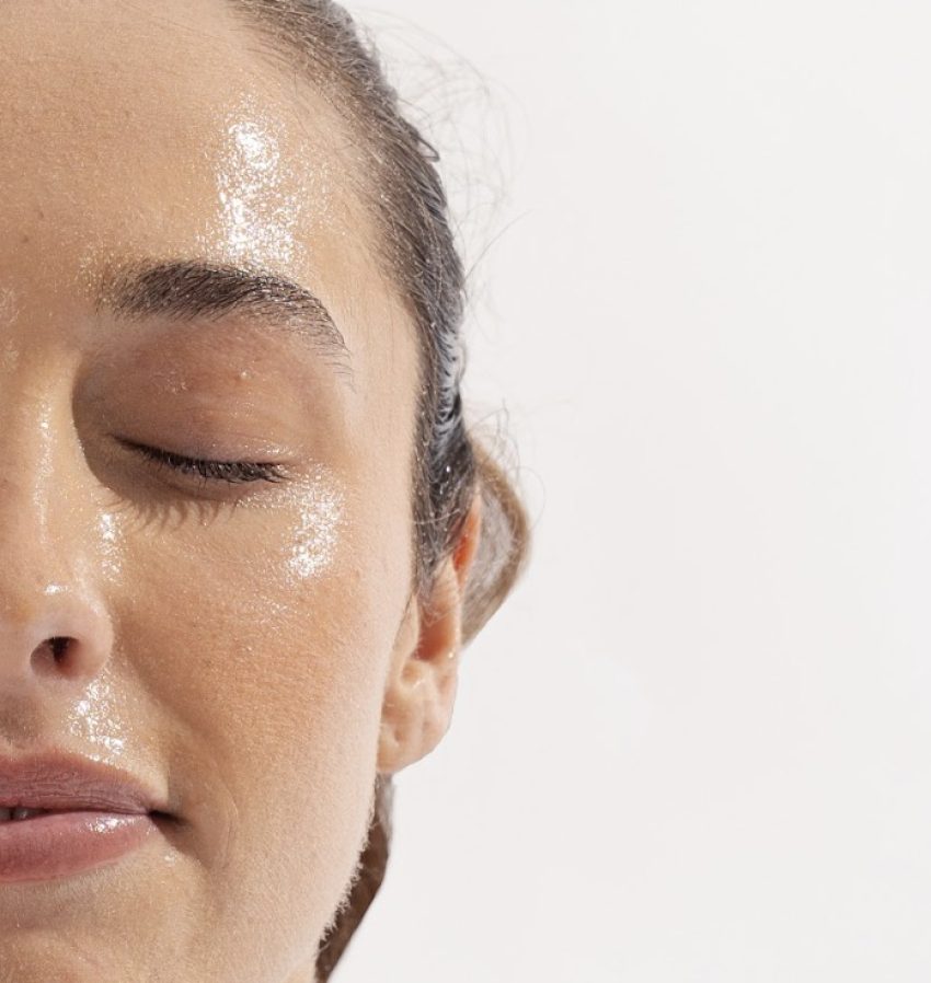 A woman with closed eyes and oil-covered face, skincare routine.