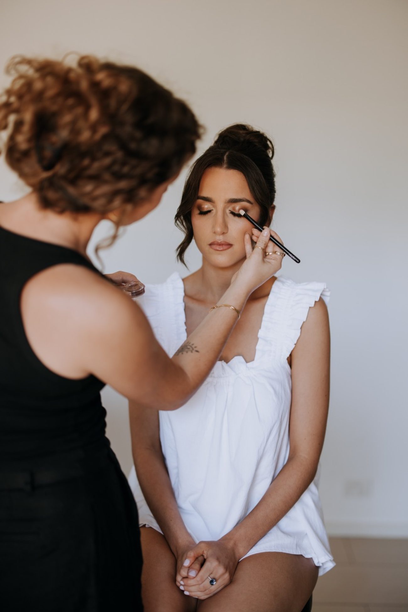 A woman getting her makeup done by another woman.