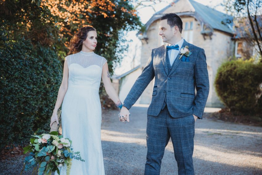 a wedding photograph of newly wed couple holding hands while staring at each other