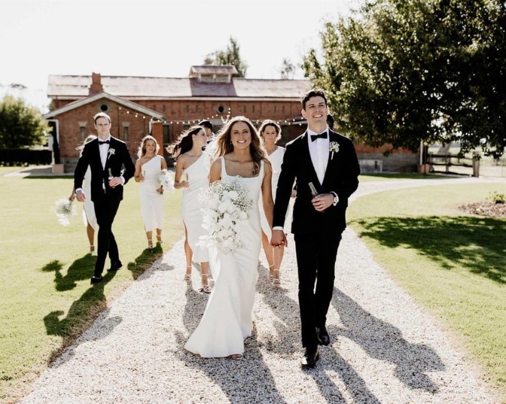 Bride and groom walk through Mewburn Park gardens with bridesmaids and groomsmen at the best wedding venue in Melbourne.