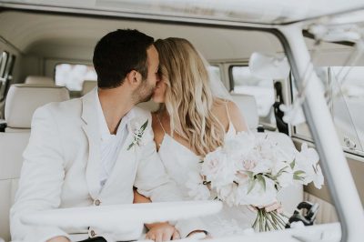 a newly wed couple kissing inside a kombi van