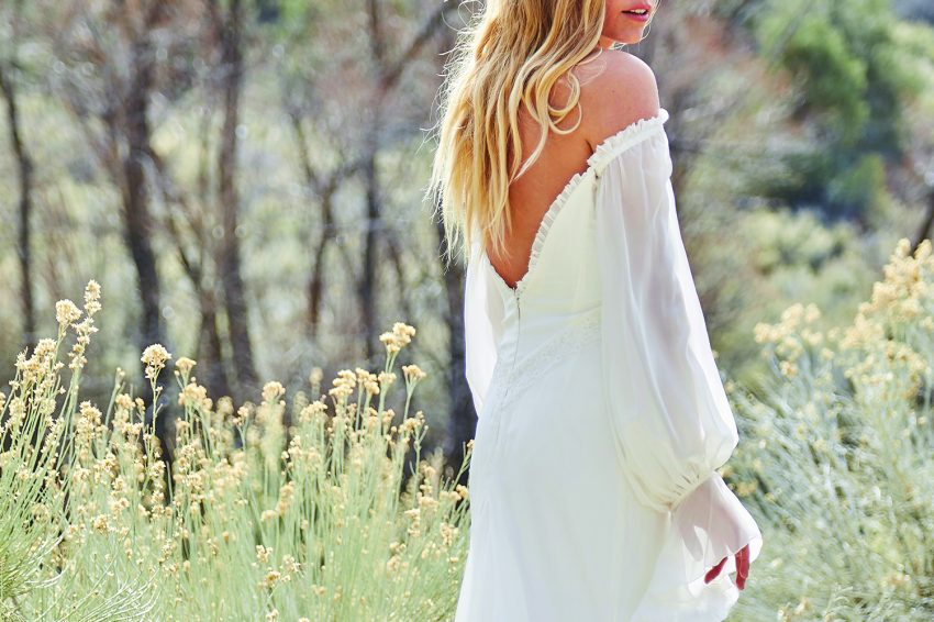 A woman wearing long sleeve wedding dress walking in the garden.