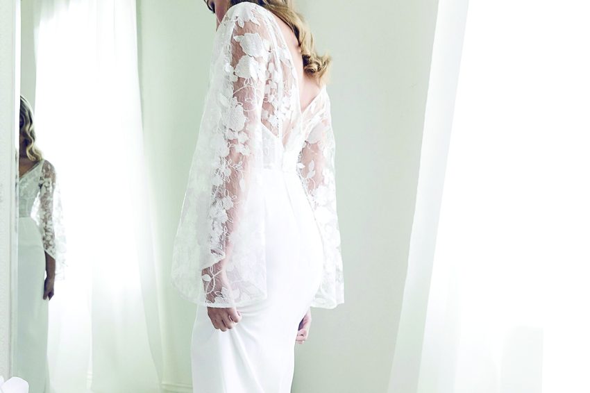 woman inside a wedding dress shop looking at her wedding dress in the mirror