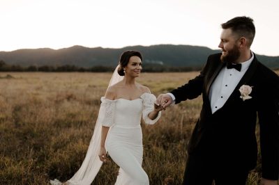 groom tagging gently the bride in a grassy field