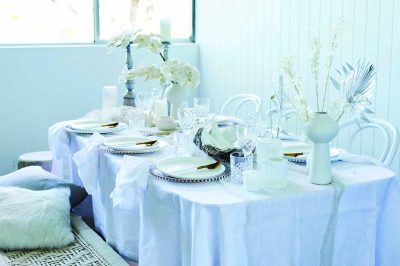 A neatly arranged table with white tablecloths and white plates, creating a clean and elegant dining atmosphere.