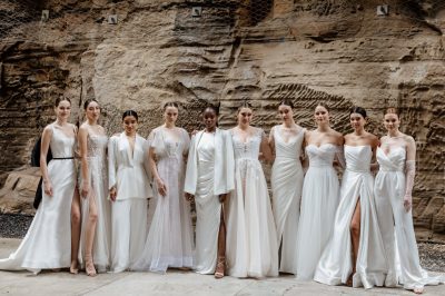 Models wearing wedding dresses posing in front of a rock wall.