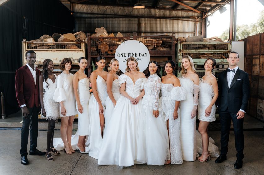 A picture of women wearing their wedding dresses and two men wearing suit beside them in a wedding fair