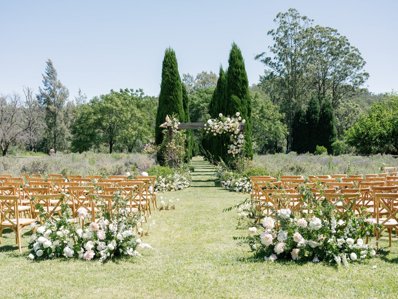 An outdoor ceremony with chairs and flowers set up for a special event.