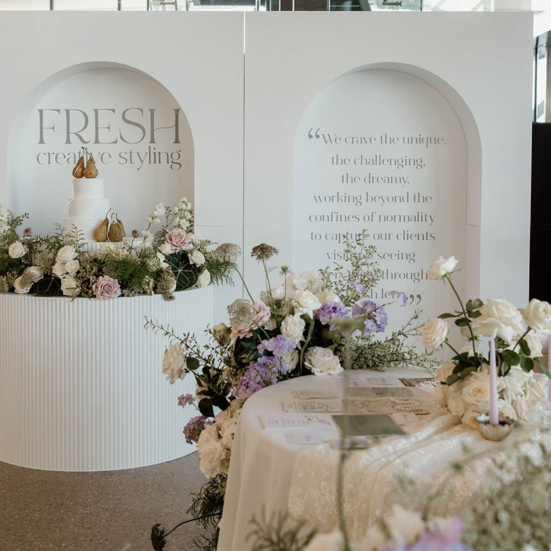 A wedding vendor stand at the wedding expo in Australia styled with flowers, candles, and cake