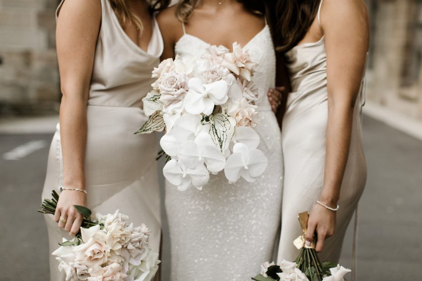 the bride and bridesmaids pose with their bouquet wedding flowers in nude and white colors