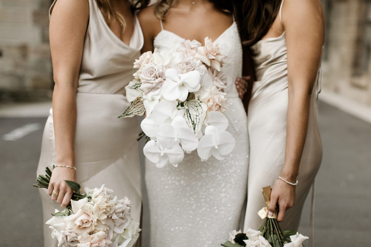 the bride and bridesmaids pose with their bouquet wedding flowers in nude and white colors