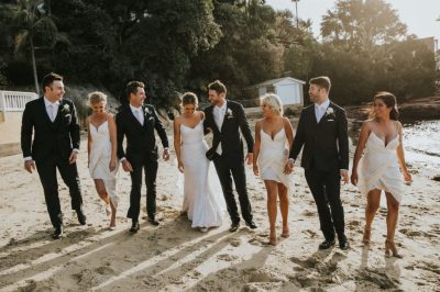 four wedding couples side by side walking along the beach