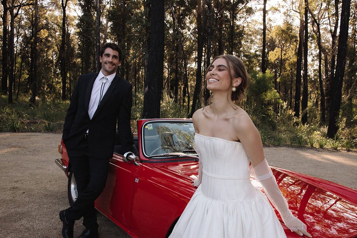 Bride and groom leaning on a red wedding car at Jackson Ranch by Bannisters wedding venue in Sydney.