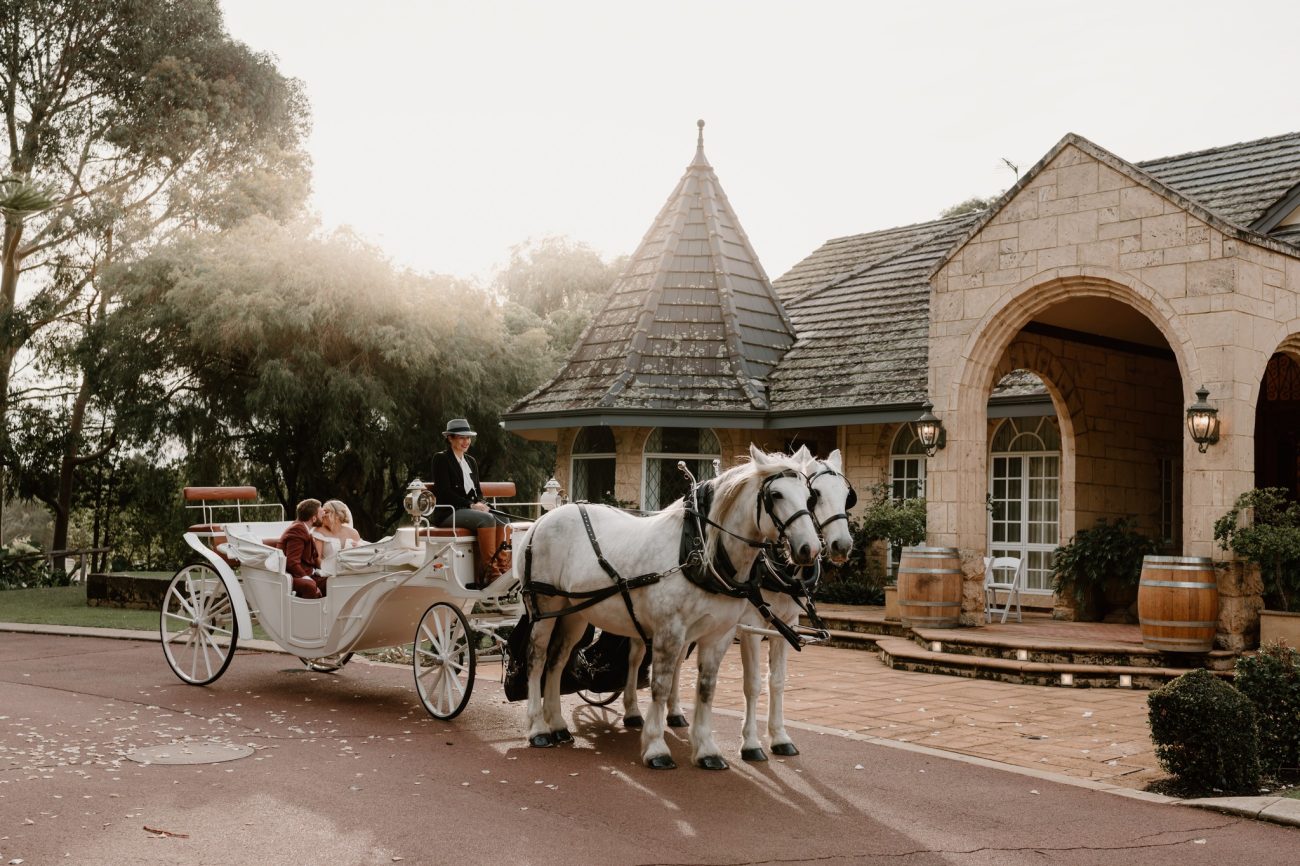 A wedding carriage being pulled by two horses.