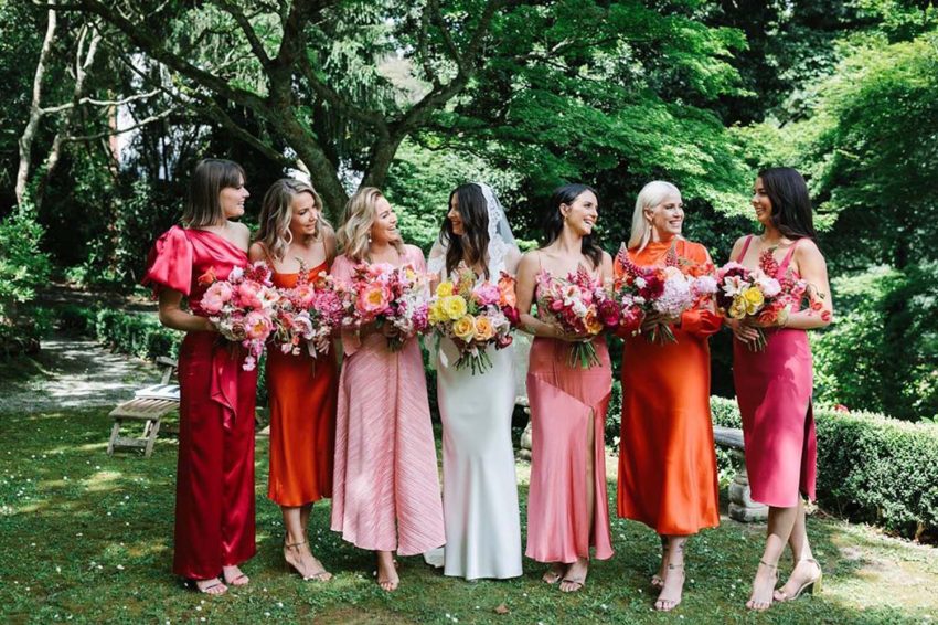 The bride and her wedding guests in their dresses posing for a photo with the bride