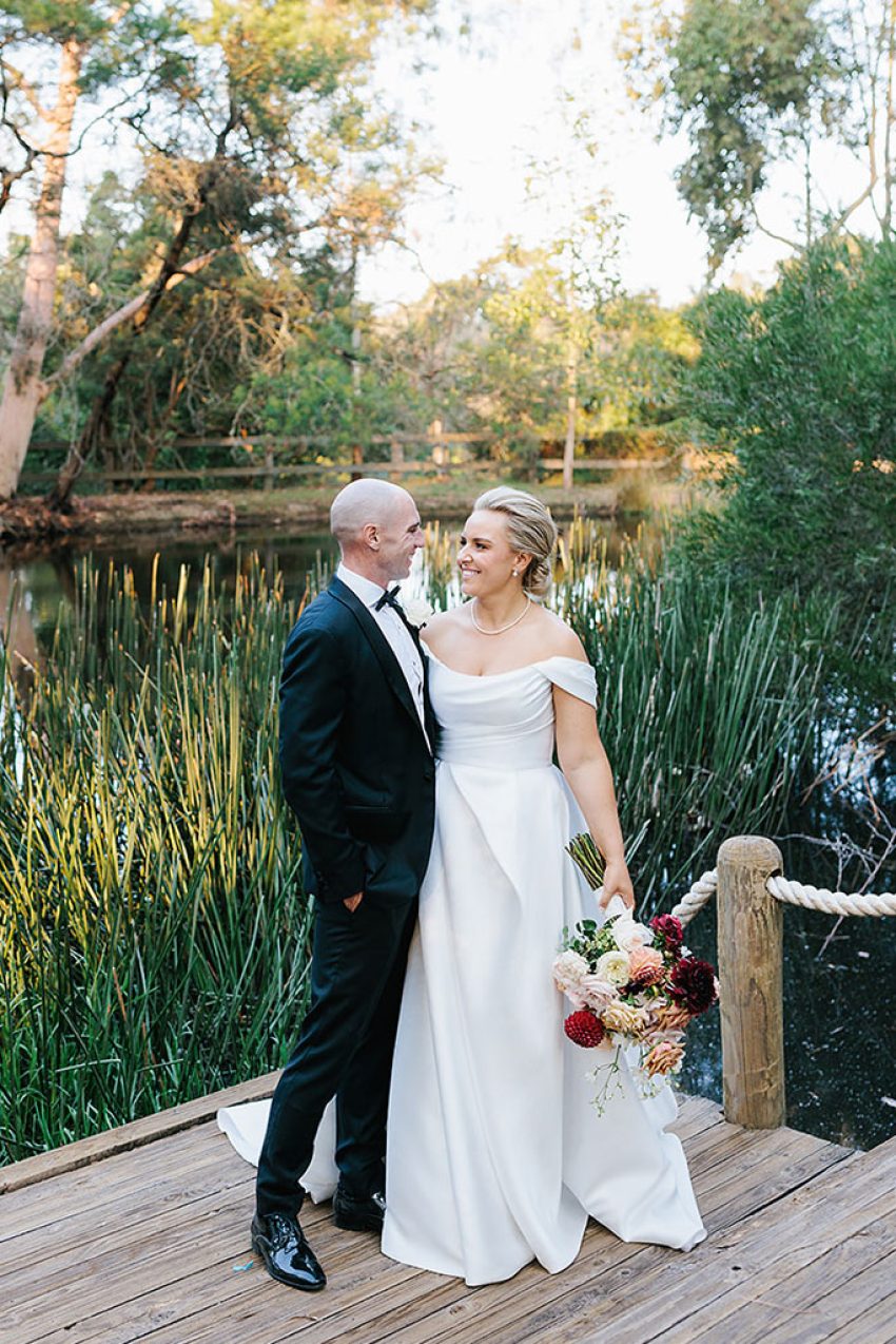 A couple posing in front of a lake.